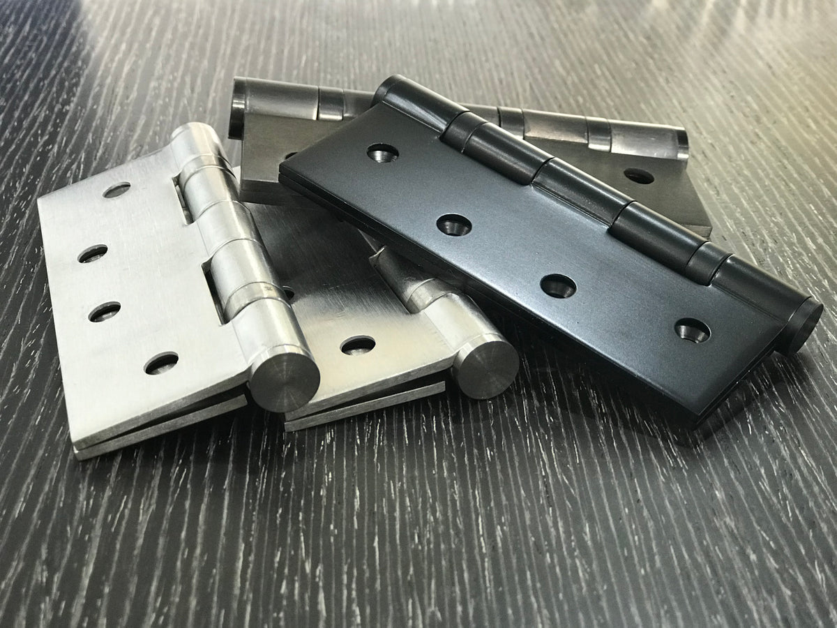 Four metal hinges on a textured wooden surface