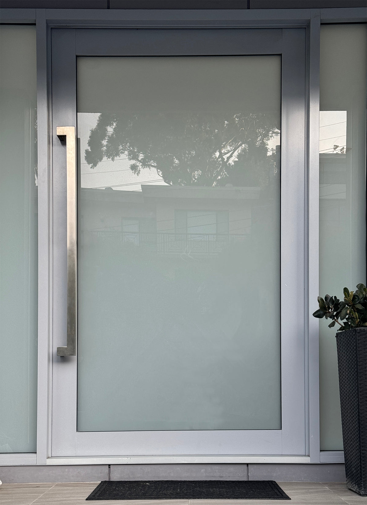 stainless steel offset pull handle on a modern entry door with a brushed stainless finish. 
