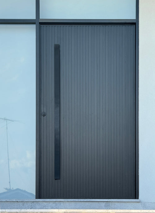 Matt black 1800mm entry door pull handle set in a urban style finish, installed on a black door 