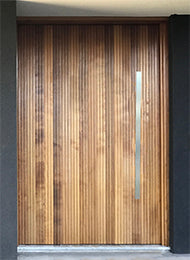 Timber door featuring a Stainless steel entry door pull handle 